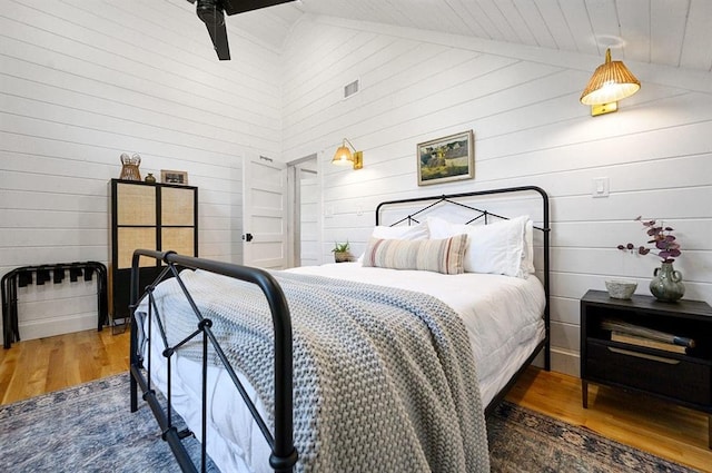 bedroom with dark wood-type flooring and wooden walls