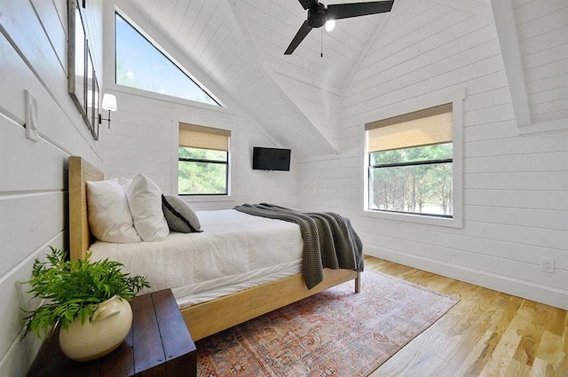 bedroom featuring hardwood / wood-style flooring, ceiling fan, wood walls, and high vaulted ceiling