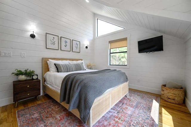 bedroom with wood walls, lofted ceiling with beams, and dark hardwood / wood-style floors