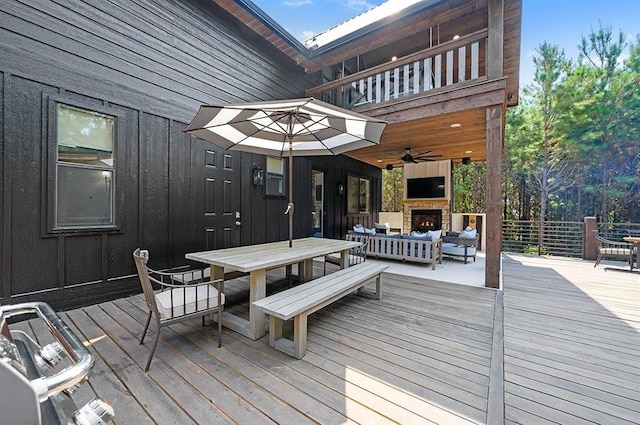 wooden terrace with an outdoor living space with a fireplace and ceiling fan