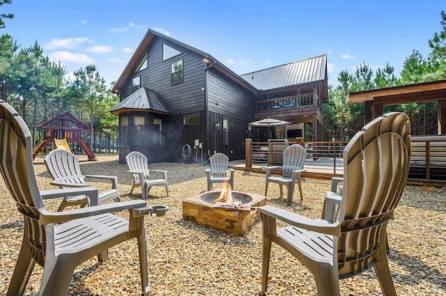 back of house featuring a playground and a fire pit