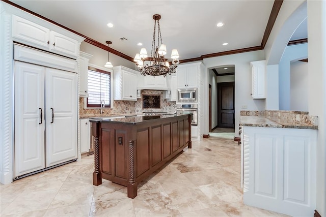 kitchen featuring white cabinetry, ornamental molding, appliances with stainless steel finishes, and dark stone counters