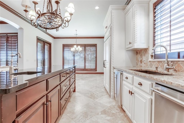 kitchen featuring light stone countertops, stainless steel dishwasher, sink, white cabinetry, and hanging light fixtures