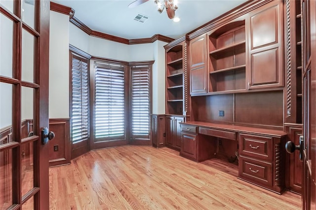 unfurnished office featuring crown molding, ceiling fan, built in desk, and light hardwood / wood-style floors