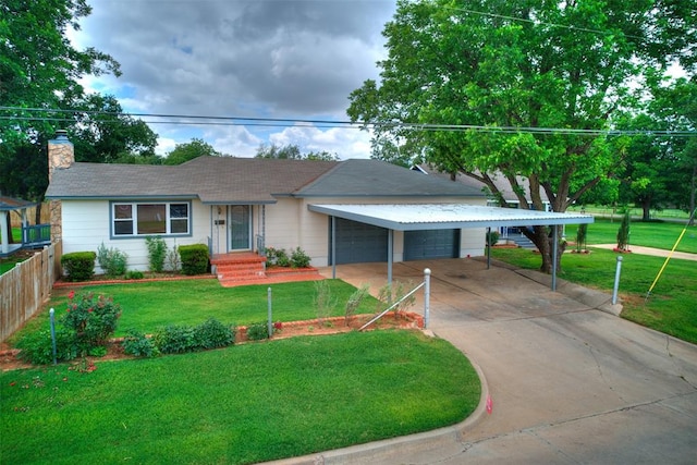 view of front of property featuring a carport, a garage, and a front lawn