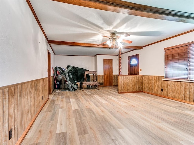 empty room with beam ceiling, wood walls, light hardwood / wood-style flooring, and ornamental molding