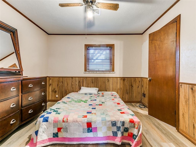 bedroom featuring ceiling fan, wooden walls, and light hardwood / wood-style flooring