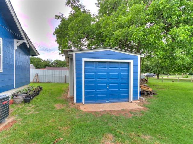 garage at dusk featuring a lawn and central air condition unit