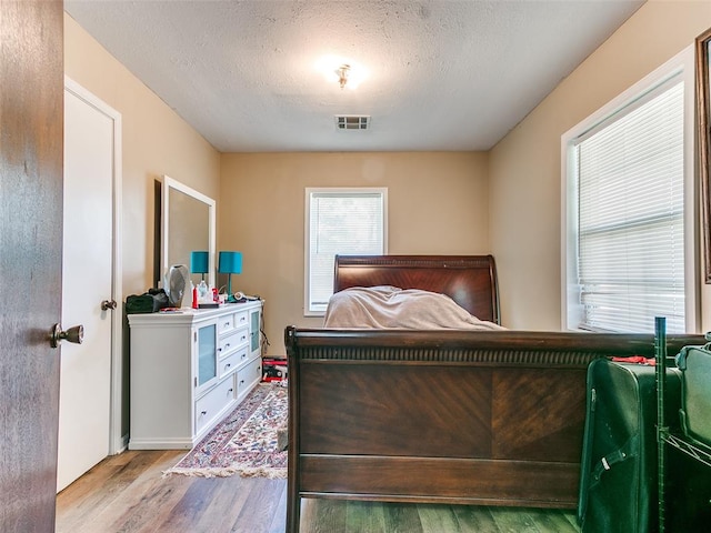 bedroom with light hardwood / wood-style flooring and a textured ceiling