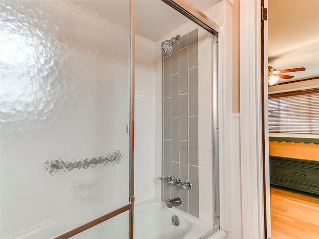 bathroom with hardwood / wood-style floors, ceiling fan, and enclosed tub / shower combo