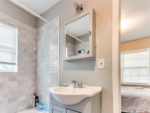 bathroom with a tile shower and vanity