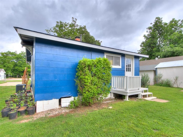 rear view of house featuring cooling unit and a lawn