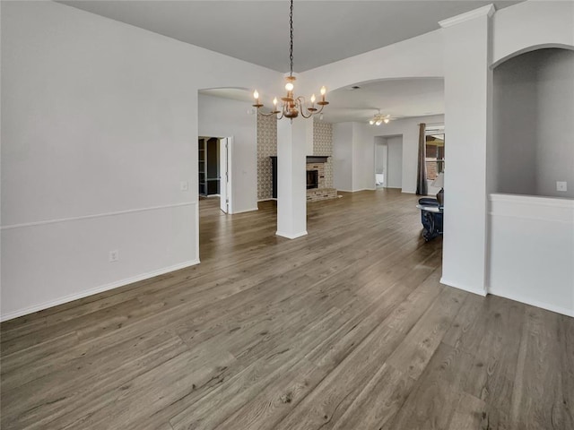 unfurnished living room with a fireplace, hardwood / wood-style flooring, and an inviting chandelier