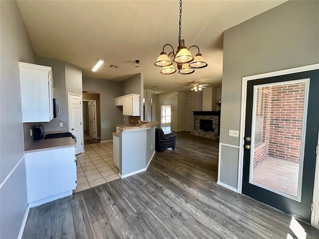 kitchen featuring range, white cabinets, a brick fireplace, light wood-type flooring, and kitchen peninsula