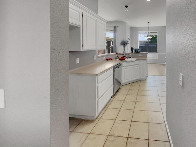 kitchen with hanging light fixtures, light tile patterned floors, stainless steel dishwasher, kitchen peninsula, and white cabinets