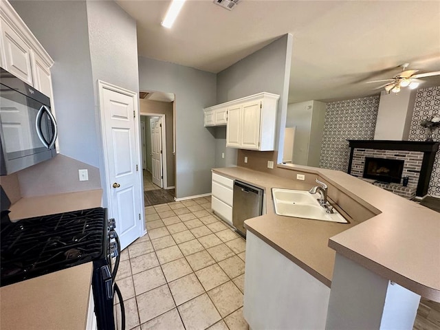 kitchen with sink, kitchen peninsula, a fireplace, white cabinetry, and stainless steel appliances