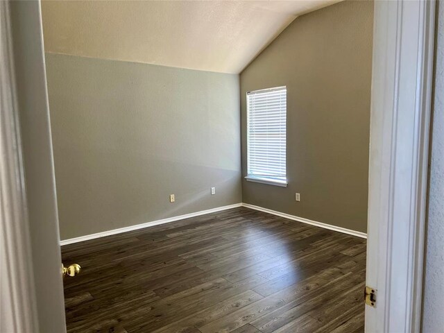 unfurnished room featuring dark wood-type flooring and lofted ceiling