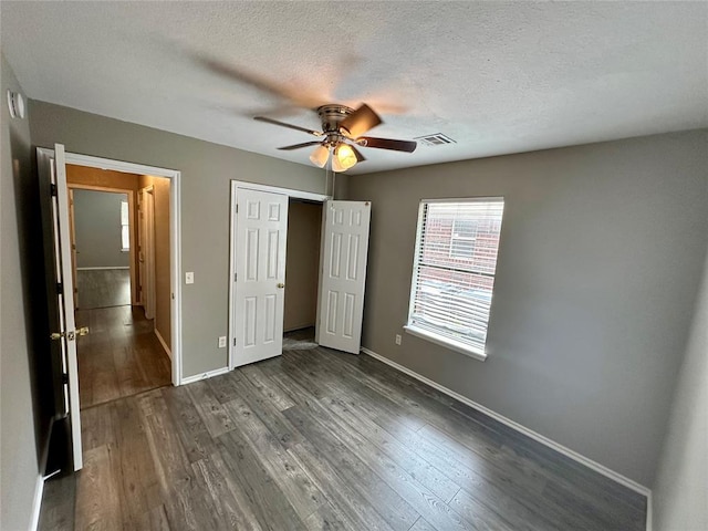 unfurnished bedroom featuring a textured ceiling, ceiling fan, and dark wood-type flooring