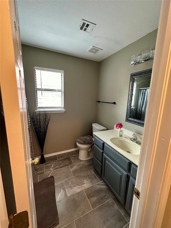 bathroom with vanity, a textured ceiling, and toilet