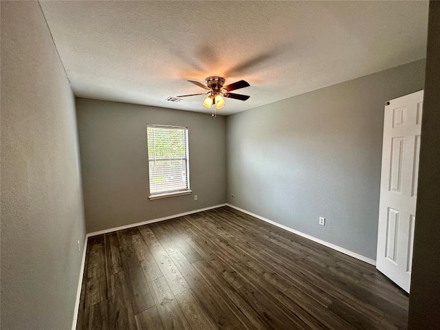 spare room with a textured ceiling, ceiling fan, and dark wood-type flooring