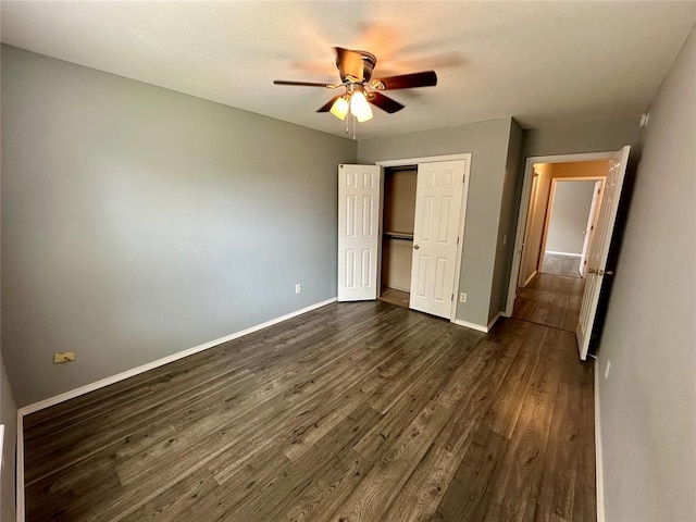 unfurnished bedroom with dark hardwood / wood-style flooring, a closet, and ceiling fan