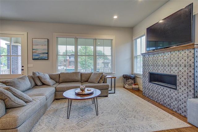 living room featuring hardwood / wood-style floors, radiator, a healthy amount of sunlight, and a tiled fireplace