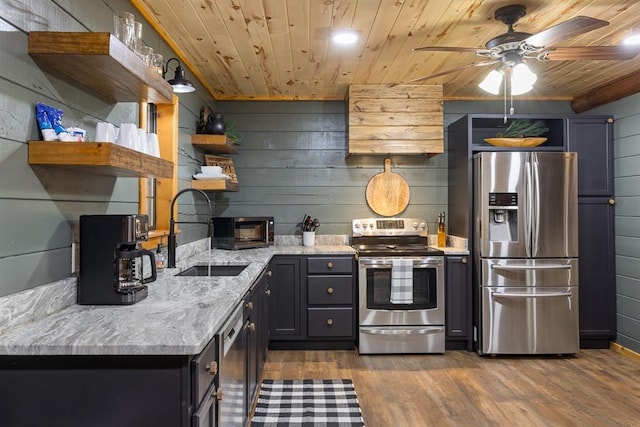 kitchen with wooden walls, sink, and stainless steel appliances