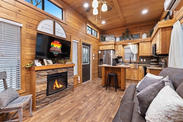 living room featuring ceiling fan, wooden walls, sink, an AC wall unit, and light hardwood / wood-style flooring