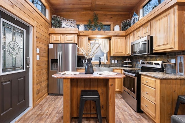 kitchen featuring a center island, sink, stainless steel appliances, wooden walls, and wood ceiling