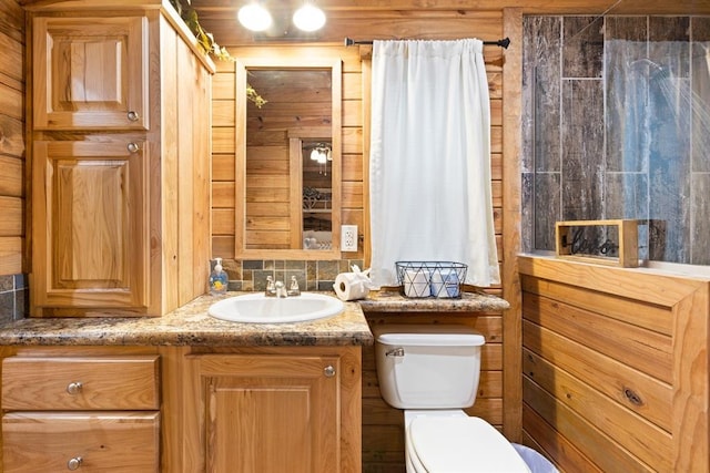 bathroom featuring vanity, toilet, wooden walls, and backsplash