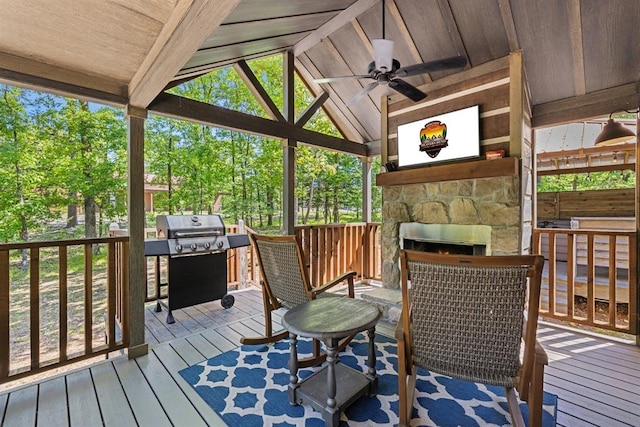 deck with an outdoor stone fireplace, area for grilling, and ceiling fan