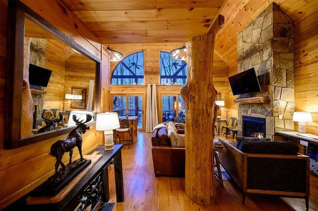 living room featuring wooden ceiling, high vaulted ceiling, hardwood / wood-style floors, wooden walls, and a fireplace