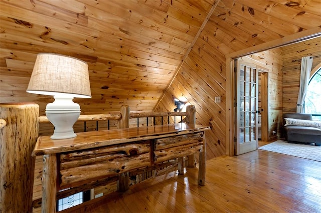 interior space featuring wooden walls, wooden ceiling, vaulted ceiling, and light wood-type flooring