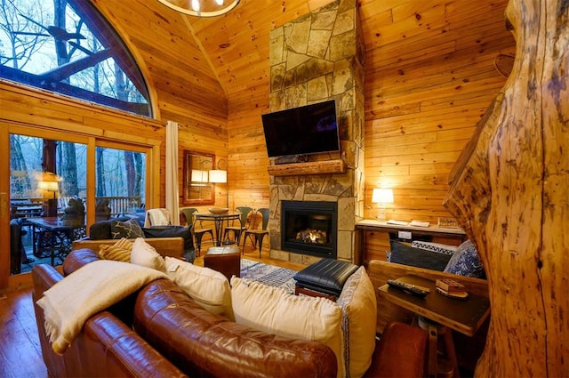 living room featuring hardwood / wood-style flooring, wood walls, a stone fireplace, and high vaulted ceiling