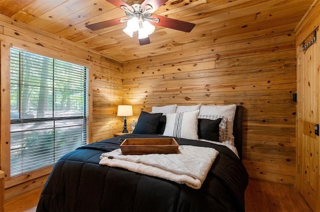 bedroom featuring ceiling fan, hardwood / wood-style floors, wooden ceiling, and wooden walls