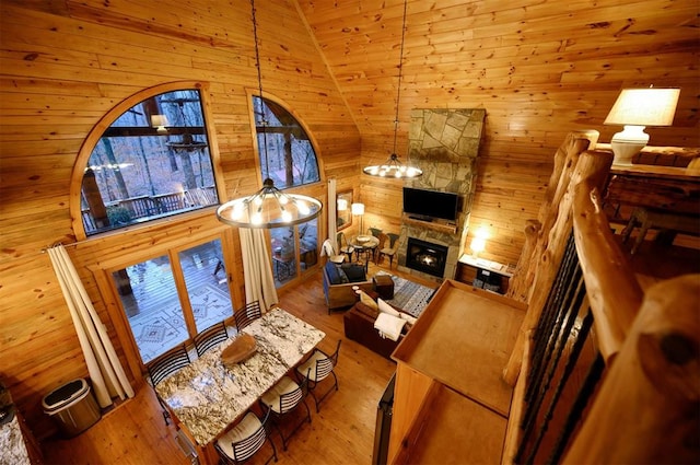 living room with a stone fireplace, wooden walls, lofted ceiling, and hardwood / wood-style flooring