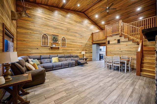 living room featuring ceiling fan, wooden walls, high vaulted ceiling, wooden ceiling, and light wood-type flooring