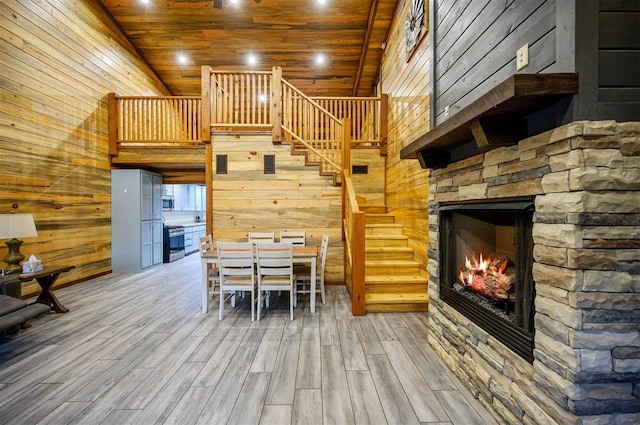 unfurnished dining area featuring a stone fireplace, hardwood / wood-style floors, and wooden ceiling