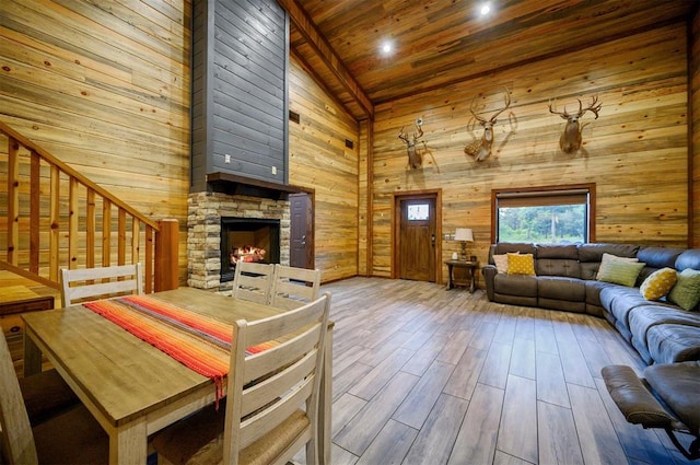 living room featuring wood ceiling, a stone fireplace, high vaulted ceiling, and hardwood / wood-style flooring