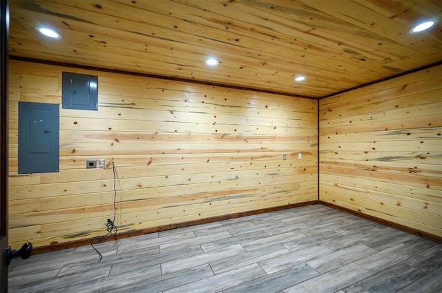 empty room with hardwood / wood-style flooring, electric panel, and wooden walls