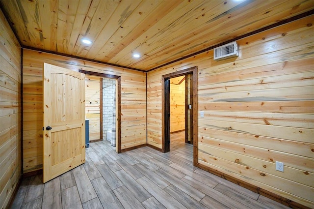 hallway with wood ceiling, wooden walls, and light hardwood / wood-style floors