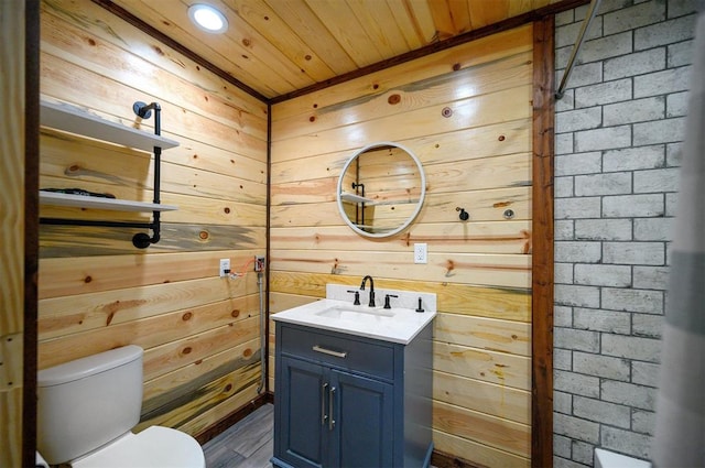 bathroom with vanity, toilet, wood ceiling, and wood walls