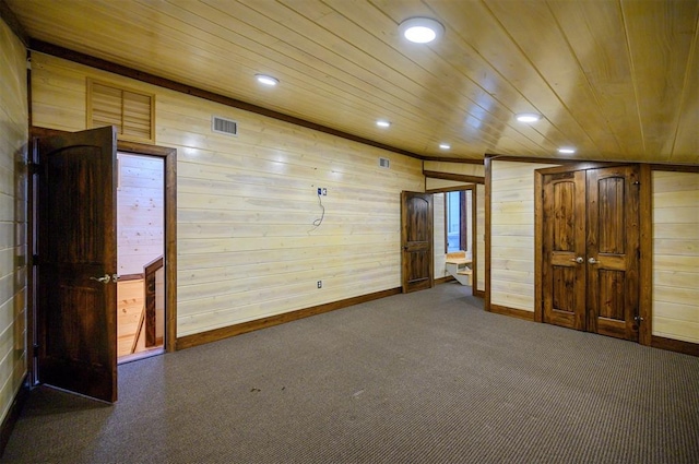 carpeted empty room with wooden walls and wooden ceiling