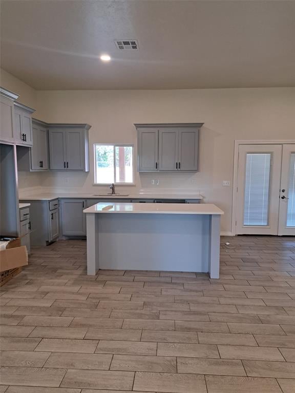 kitchen with gray cabinetry, light hardwood / wood-style flooring, french doors, and sink