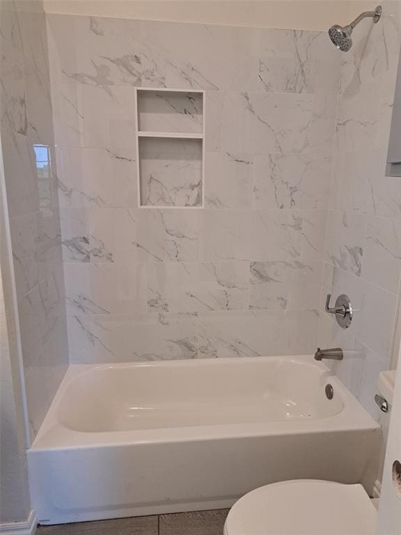 bathroom with tiled shower / bath combo and toilet