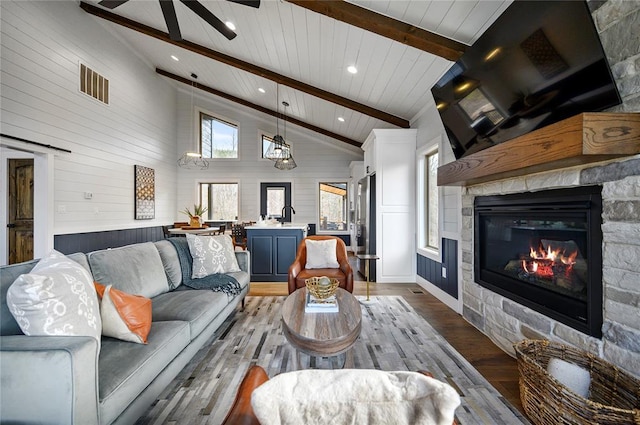 living room with beamed ceiling, light hardwood / wood-style floors, a barn door, a fireplace, and high vaulted ceiling