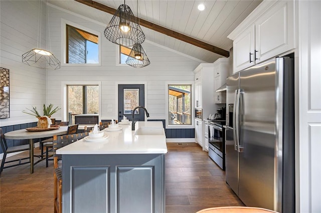 kitchen with hanging light fixtures, stainless steel appliances, an island with sink, white cabinets, and sink