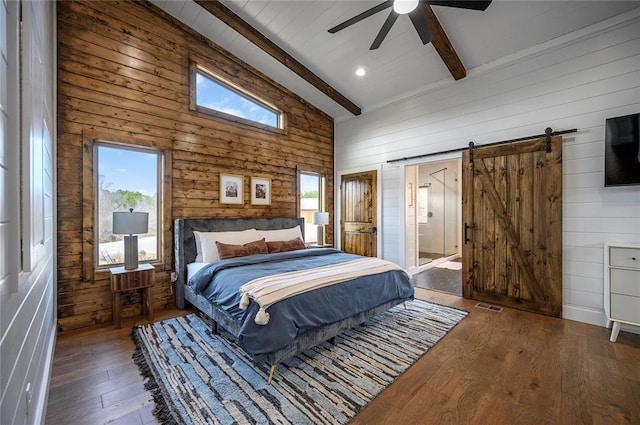 bedroom featuring multiple windows, a barn door, and beam ceiling