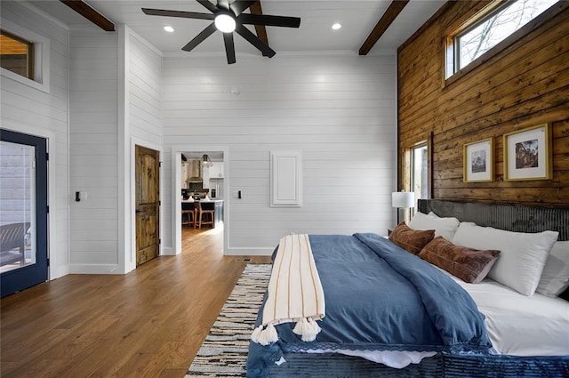 bedroom featuring a high ceiling, hardwood / wood-style floors, ceiling fan, and beam ceiling