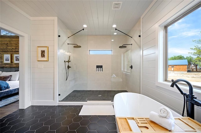 bathroom with a healthy amount of sunlight, wood walls, and independent shower and bath